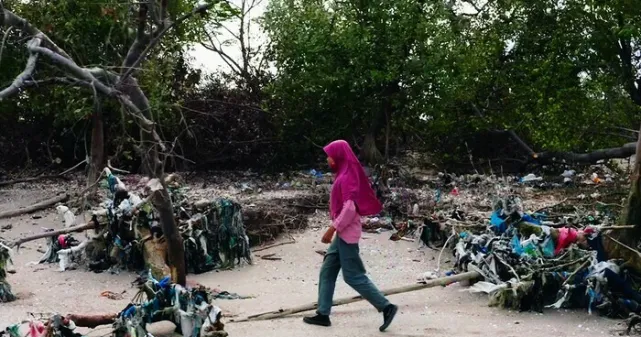 Petite fille qui marche au milieu des déchets plastiques sur une plage
