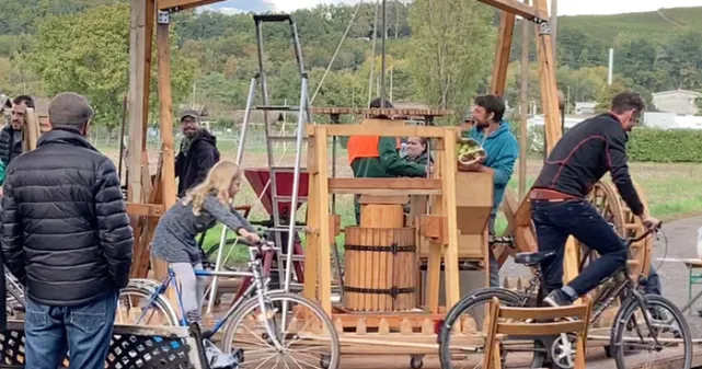 Des hommes, femmes et enfants sont sur des vélos et font tourner le pressoir à jus de l'association Label Vie.