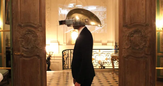 Photographie du casque interactif en aluminium porté par un homme devant une porte.