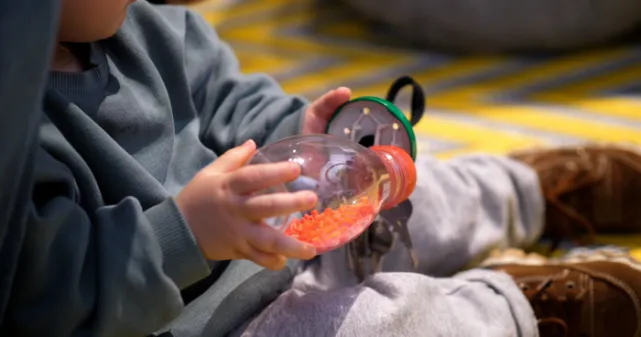 Un bébé découvre avec ses mains un hochet fait avec des objets recyclés