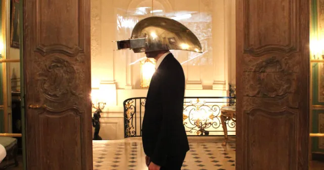 Photographie du casque interactif en aluminium porté par un homme devant une porte,